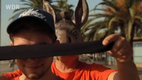 Ein Mann mit einer Eselsmaske verbindet Lukas die Augen. Rechte: WDR