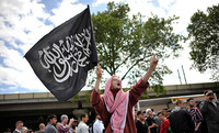 Ein Mann hält bei der salafistischen Demonstration eine schwarze Flagge mit arabischer Schrift hoch.