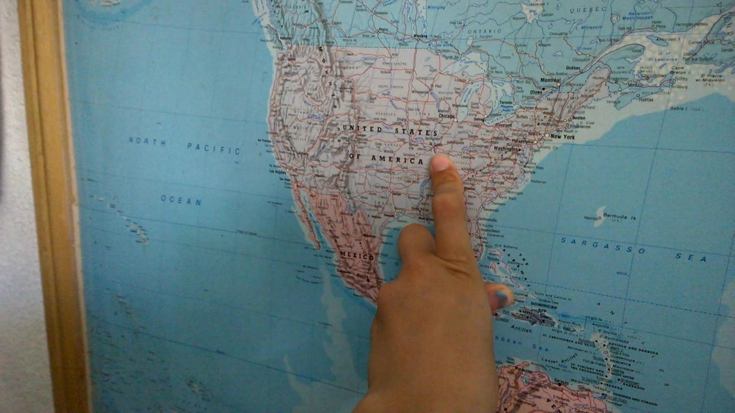 Eine Hand zeigt einen Ort auf einer Karte der USA.