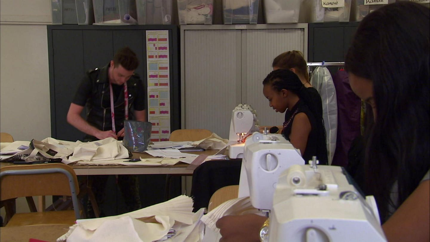 Junge Menschen in einer Werkstatt arbeiten mit Stoffen an Nähmaschinen. (Foto: WDR - Screenshot aus der Sendung)