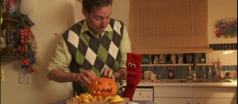 Ein Mann und eine rote Strumpfhandpuppe höhlen einen Kürbis für Halloween aus. (Foto: WDR - Screenshot aus der Sendung)
