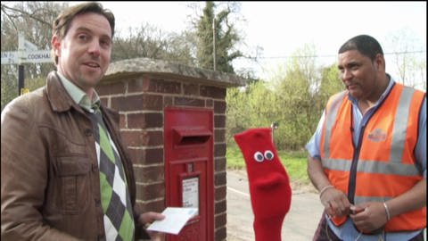 Ein Mann steht vor einem Briefkasten. Neben ihm eine rote Strumpfhandpuppe und ein Postbote. (Foto: WDR - Screenshot aus der Sendung)