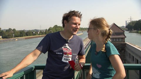 Ein Mann und eine Frau stehen auf einer Brücke und lachen miteinander.  (Foto: WDR - Screenshot aus der Sendung)