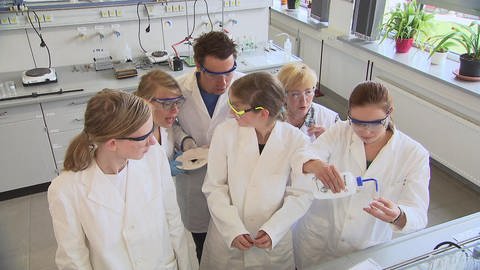 Sechs Personen stehen in weißen Kitteln in einem Labor und experimentieren. (Foto: SWR / BR / WDR - Screenshot aus der Sendung)