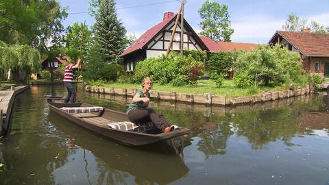 Eine Frau sitzt auf einem Kahn, ein Mann drückt das Boot mit einem langen Stock vom Boden weg. (Foto: SWR / BR / WDR - Screenshot aus der Sendung)