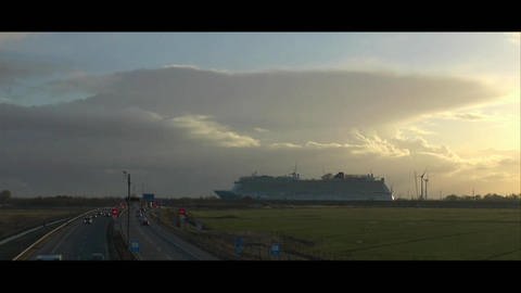Links eine Autobahn, rechts im Hintergrund ein großes Schiff, davor grüne Felder. (Foto: SWR / BR / WDR - Screenshot aus der Sendung)