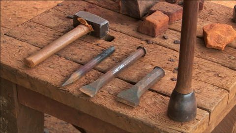 Auf einem Tisch liegen ein Hammer und drei unterschiedliche Meißel. (Foto: WDR / SWR - Screenshot aus der Sendung)