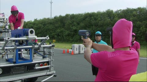 Eine Person zielt mit einer Laserpistole zur Geschwindigkeitsbestimmung auf eine Ballwurfmaschine. (Foto: SWR - Screenshot aus der Sendung)