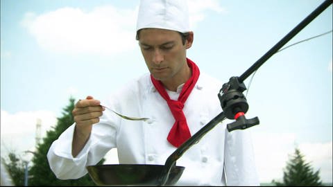 Ein Koch probiert Essen aus einer Pfanne. (Foto: SWR - Screenshot aus der Sendung)
