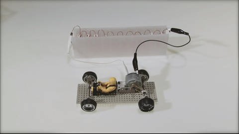 Ein Modellauto ist an eine Batterie angeschlossen. (Foto: SWR - Screenshot aus der Sendung)