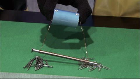 Ein Nagel ist umwicket mit Kupferdraht und wird damit an eine Batterie angeschlossen. Der Nagel ist nun magnetisch. (Foto: SWR - Screenshot aus der Sendung)