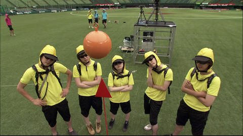 Gelb gekleidete Personen stehen auf einem Sportplatz und beobachten ein Pendel. (Foto: SWR - Screenshot aus der Sendung)