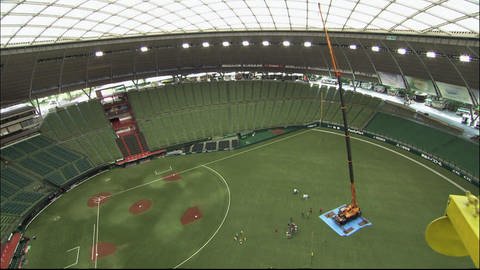 Luftaufnahme eines Baseballstadions. Auf dem Rasen steht ein großer Kran. (Foto: SWR - Screenshot aus der Sendung)