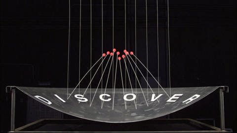 Eine Computeranimation: auf eine gewölbte Schalle prasseln rote Bälle ein. Ihre Flugkurven sind eingezeichnet. Auf der Schale steht DISCOVER. (Foto: SWR)