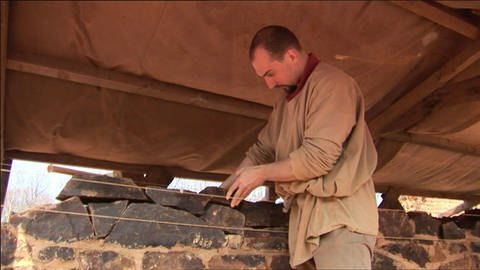 Ein Mann setzt Steine aufeinander und baut eine Mauer. (Foto: WDR / SWR - Screenshot aus der Sendung)