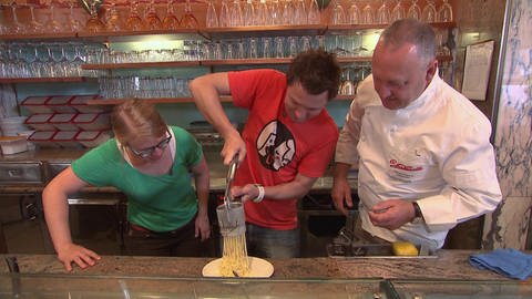 Drei Personen stehen in einem Eiscafé und bereiten Spaghetti Eis zu. (Foto: SWR / BR / WDR - Screenshot aus der Sendung.)