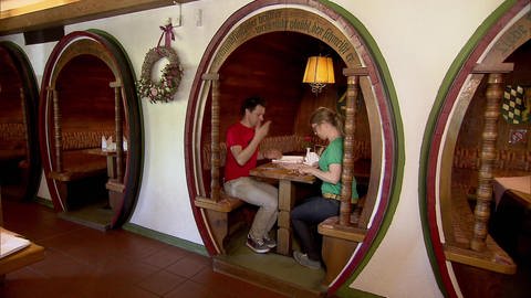 Zwei Personen sitzen in einem zu einer Sitzecke umgebauten Weinfass in einem Restaurant.  (Foto: SWR / BR / WDR - Screenshot aus der Sendung)