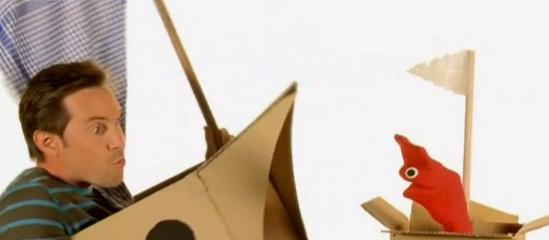 Englisch für die Grundschule: David und die rote Strumpfhandpuppe Red in Schiffen aus Pappe. (Foto: WDR - Screenshot aus der Sendung)