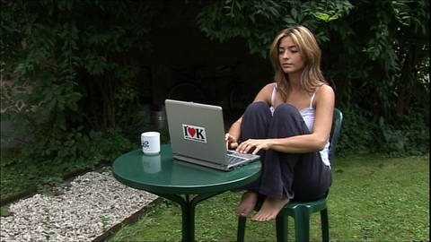 Eine junge Frau sitzt im Garten an einem kleinen Tisch und schreibt auf ihrem Laptop. (Foto: WDR)