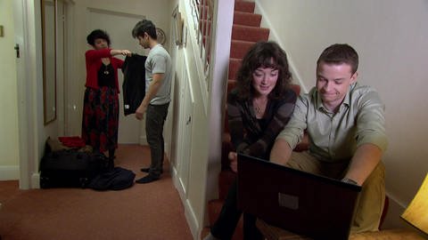 Ein junger Mann und eine junge Frau sitzen auf einer Treppe und schauen auf einen Computer. Neben der Treppe probieren zwei andere junge Erwachsene Kleidung an. (Foto: WDR)
