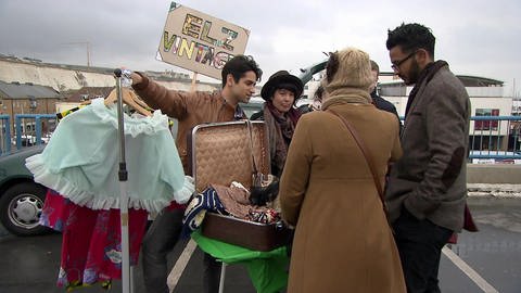 Vier junge Leute stehen an einem Stand auf dem Flohmarkt, vor ihnen viele Kleidungsstücke. (Foto: WDR)