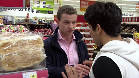 Zwei junge Männer stehen in einem Supermarkt und unterhalten sich mit ernstem Gesichtsausdruck. (Foto: WDR)