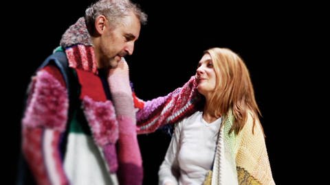 Zwei Schauspieler stehen nebeneinander auf der Bühne, ein Mann und eine Frau in bunten, einfachen Gewändern. (Foto: WDR)