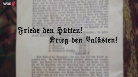 Eine verschwommene Fotografie eines Aufsatzes, davor schwebt der Schriftzug "Friede den Hütten! Krieg den Palästen!". (Foto: WDR)