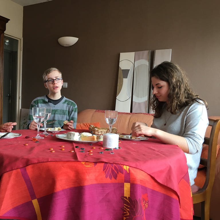 Drei junge Menschen sitzen an einem Tisch. (Foto: WDR/UR)