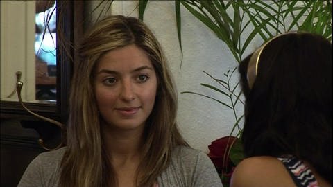 Zwei junge Frauen sitzen in einem Café und unterhalten sich.