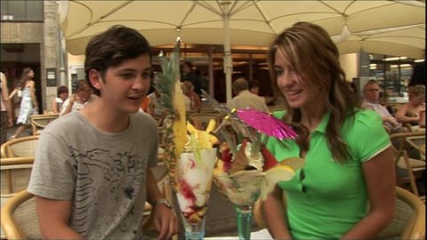 Ein junger Mann und eine junge Frau sitzen gemeinsam in einem Eis-Café.