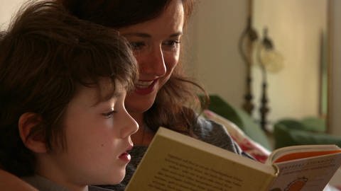 Eine Frau liest einem Jungen aus einem Buch vor.