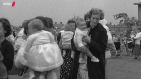 Schwarz-weiß Foto von vielen Frauen mit Kindern auf dem Arm.