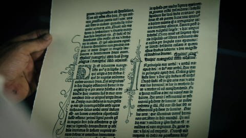 Eine Hand hält eine gedruckte Seite aus einem alten Buch