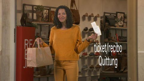 Eine Frau steht mit einer Einkaufstüte und einem Kassenzettel in der Hand im Eingang eines Schuhgeschäfts. Neben ihr der Schriftzug "ticketrecibo, Quittung". (Foto: WDR)