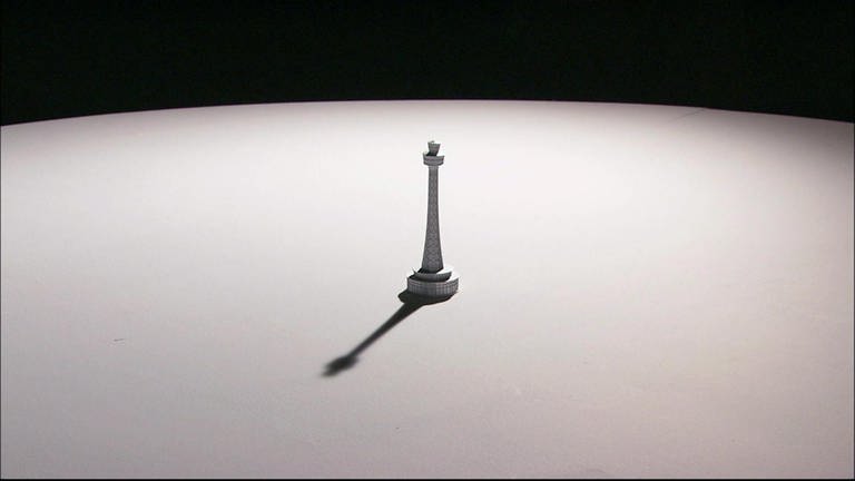 Eine kleine Figur wirft einen Schatten auf einen Tisch.
