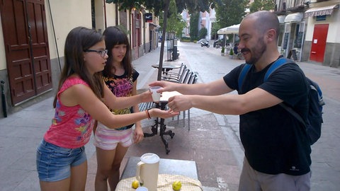 Zwei Mädchen verkaufen einem Mann Limonade.