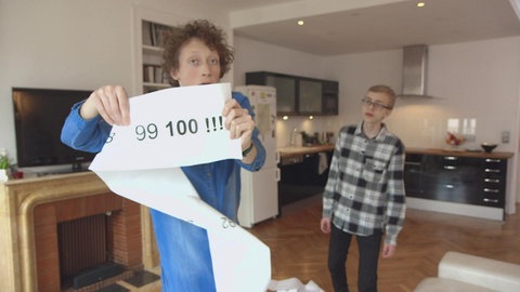 Ein junger Mann hält eine Schriftrolle hoch, darauf stehen die Zahlen bis 100.