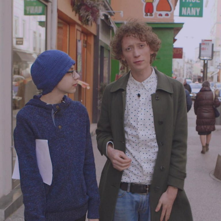 Ein junger Mann und ein Junge laufen gemeinsam durch eine Stadt.