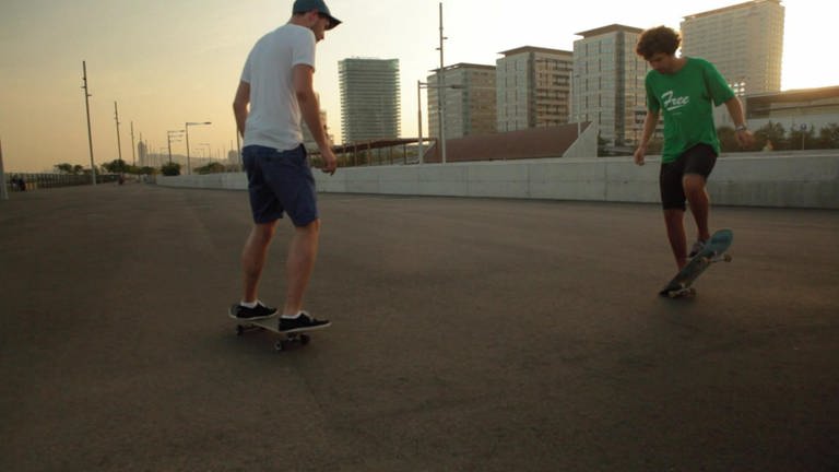 Zwei Jungen auf einem Skateboard.