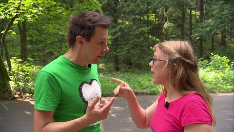 Ein Mann und eine Frau unterhalten sich und zeigen mit dem Finger aufeinander.