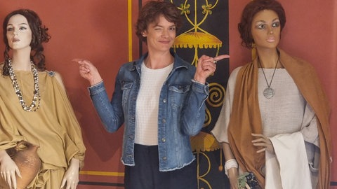 Moderatorin Lena Ganschow zwischen zwei in römische Togen gekleidete Schaufensterpuppen