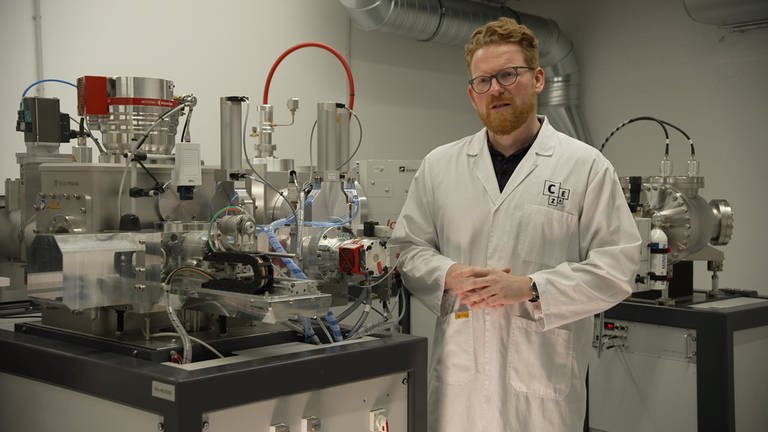 Wissenschaftler Ronny Friedrich steht neben einem Teilchenbeschleuniger