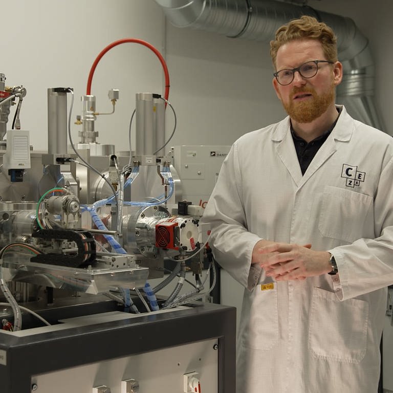 Wissenschaftler Ronny Friedrich steht neben einem Teilchenbeschleuniger