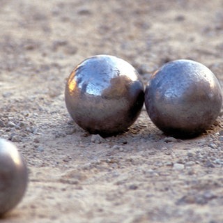 Drei Bocciakugeln auf sandigem Boden