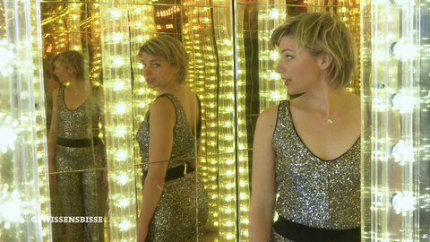 Die Moderatorin steht in einem Spiegelkabinett.