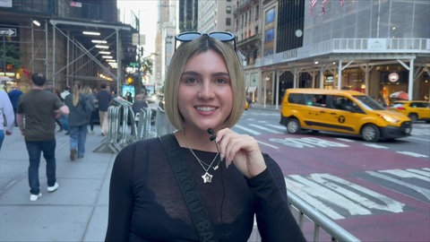 Lily auf einer Straße in New York. Im Hintergrund viele Menschen und gelbe Taxis