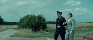 Spielszene: Wernher von Braun in SS-Uniform hat seine Sekretärin untergehakt. Der Ingenieur baut im Zweiten Weltkrieg Raketen für Hitler.