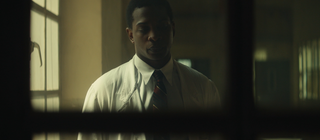 Spielszene: Frantz Fanon in weißem Arztkittel: Auch als Psychiater kämpft er gegen die Folgen von Kolonialisierung und Krieg.