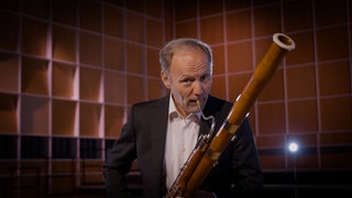 Ein Mann spielt Fagott. Das Instrument gehört zu den Holzblasinstrumenten.